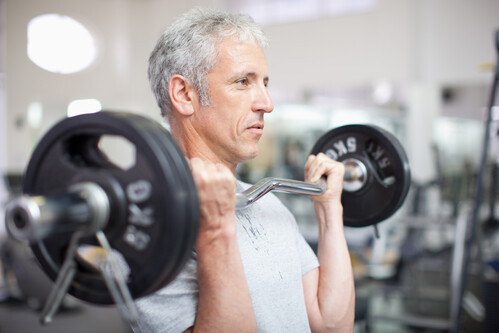 Portrait of smiling man holding barbell in gymnasium not enough energy to exercise